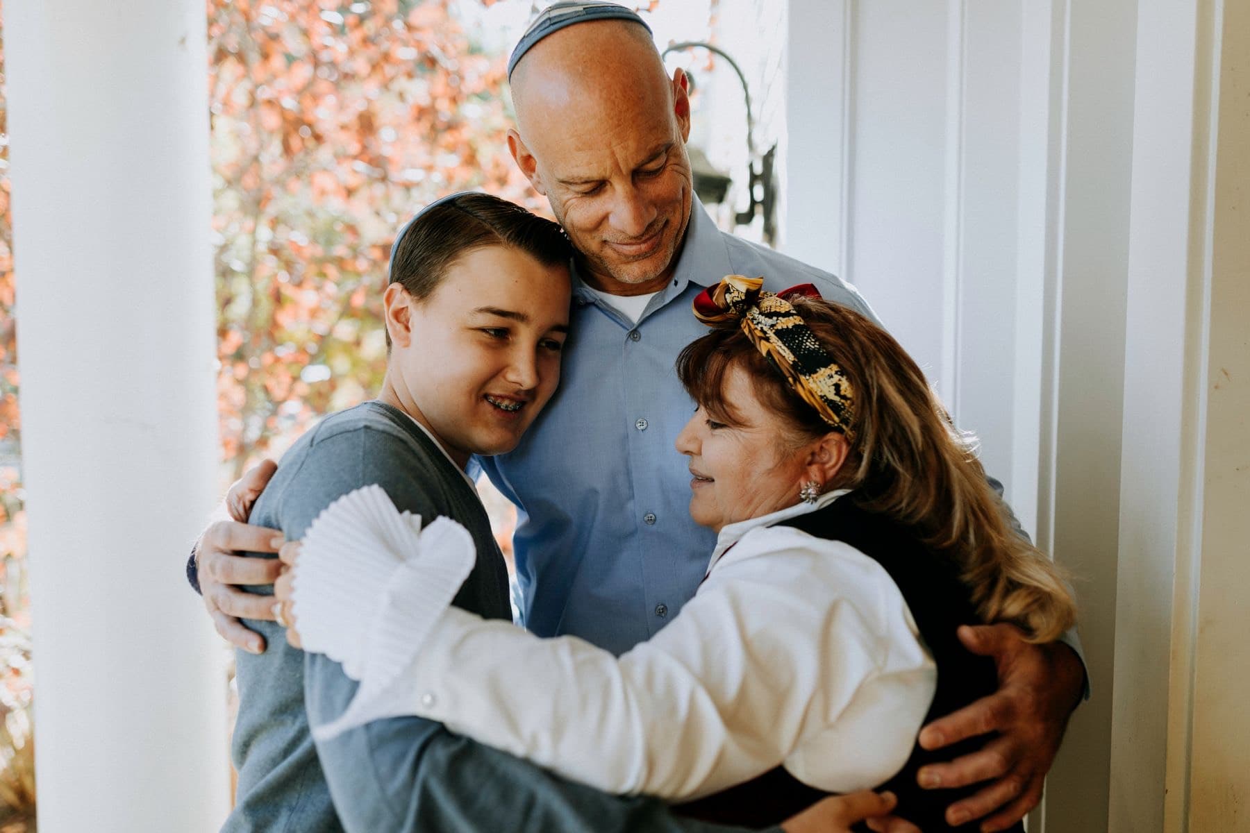 Grandfather in a kippah hugging his two grandchildren